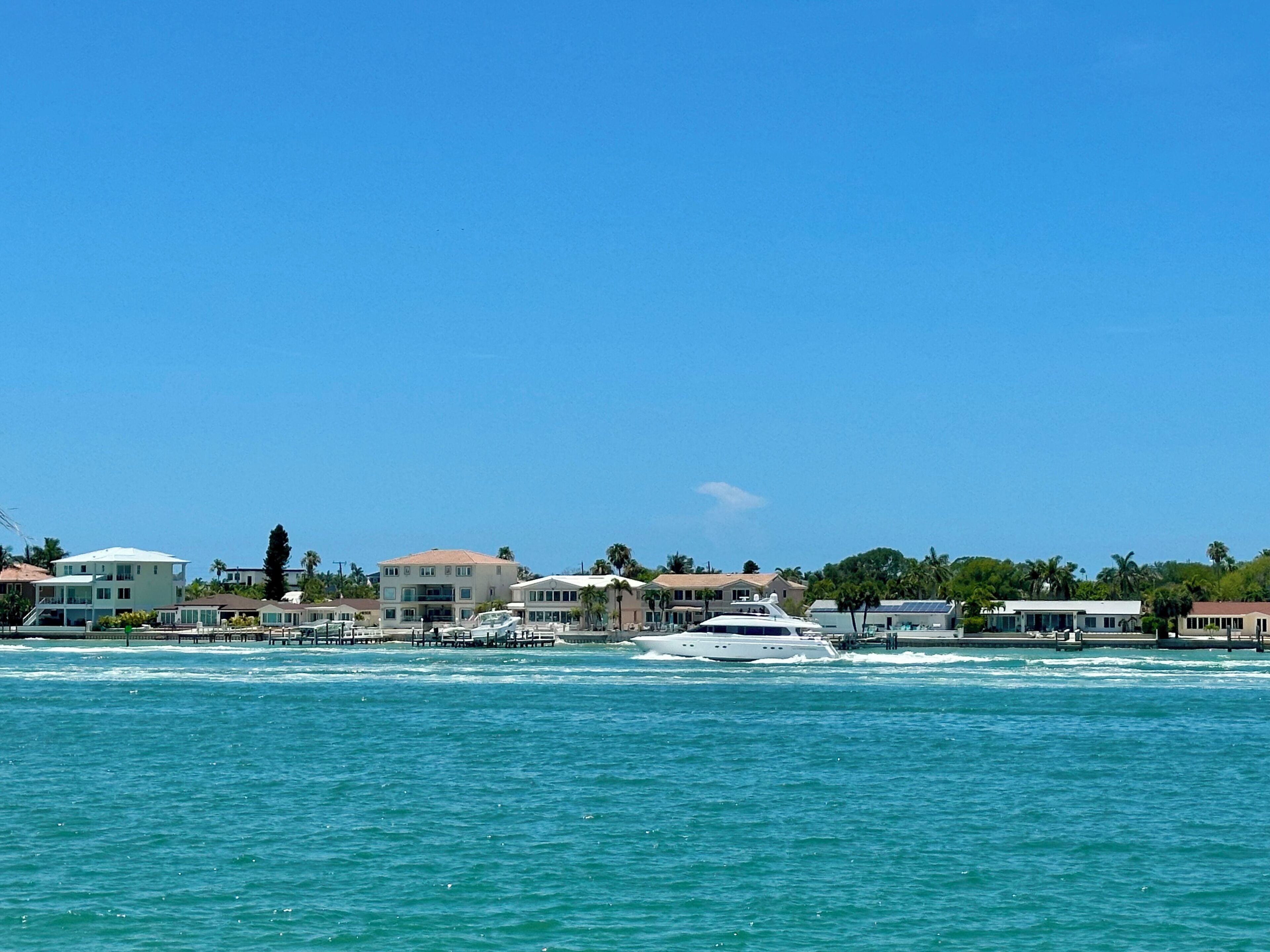 A coastal view with a marina, houses, and a clear sky.