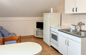 A compact kitchen with a refrigerator, stove, sink, and a small television. - Beautiful apartment in Rab with WiFi (Rab)