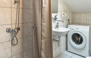 A bathroom with a shower, sink, and washing machine. - Beautiful apartment in Rab with WiFi (Rab)