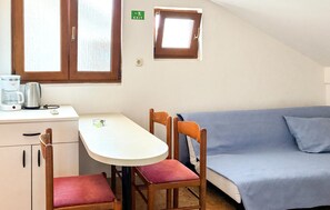A small kitchenette with a coffee maker, a table, and a chair. There is a window with a view of the outside. - Beautiful apartment in Rab with WiFi (Rab)