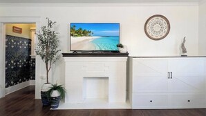Een woonkamer met een open haard, een televisie, een kast en een decoratief wandobject.