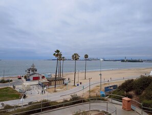 A coastal view with a beach, palm trees, and a distant port. - CozyVibeStay. Walk to Sand. Workspace. Parking (Long Beach)