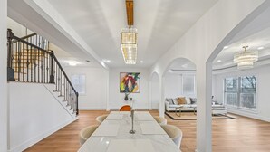 A spacious living area with a dining table, a staircase, and a chandelier. - New 8bd 7.5ba 6,600 sq ft Home in O4W Inman Park WALKABLE ATL Eastside Beltline (Atlanta)
