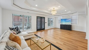 A spacious living room with a large window, a sofa, a coffee table, and a TV. - New 8bd 7.5ba 6,600 sq ft Home in O4W Inman Park WALKABLE ATL Eastside Beltline (Atlanta)