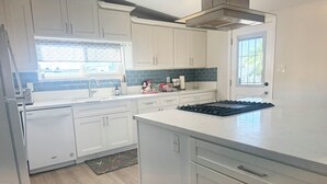 Una cocina moderna con armarios blancos, una campana extractora de acero inoxidable y una isla grande con placa de cocina negra.