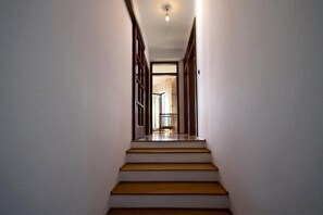 Ein schmaler Flur mit einer Holztreppe, die zu einem Raum mit einer Tür führt.