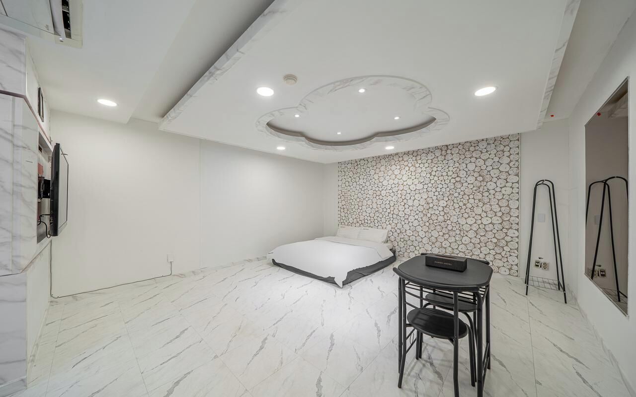 Un dormitorio con una cama, una mesita y una silla.