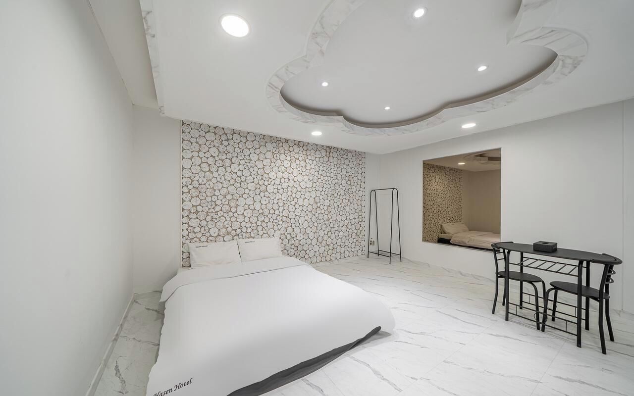 Una habitación de hotel moderna con una cama grande, un área de comedor y un diseño de techo único.