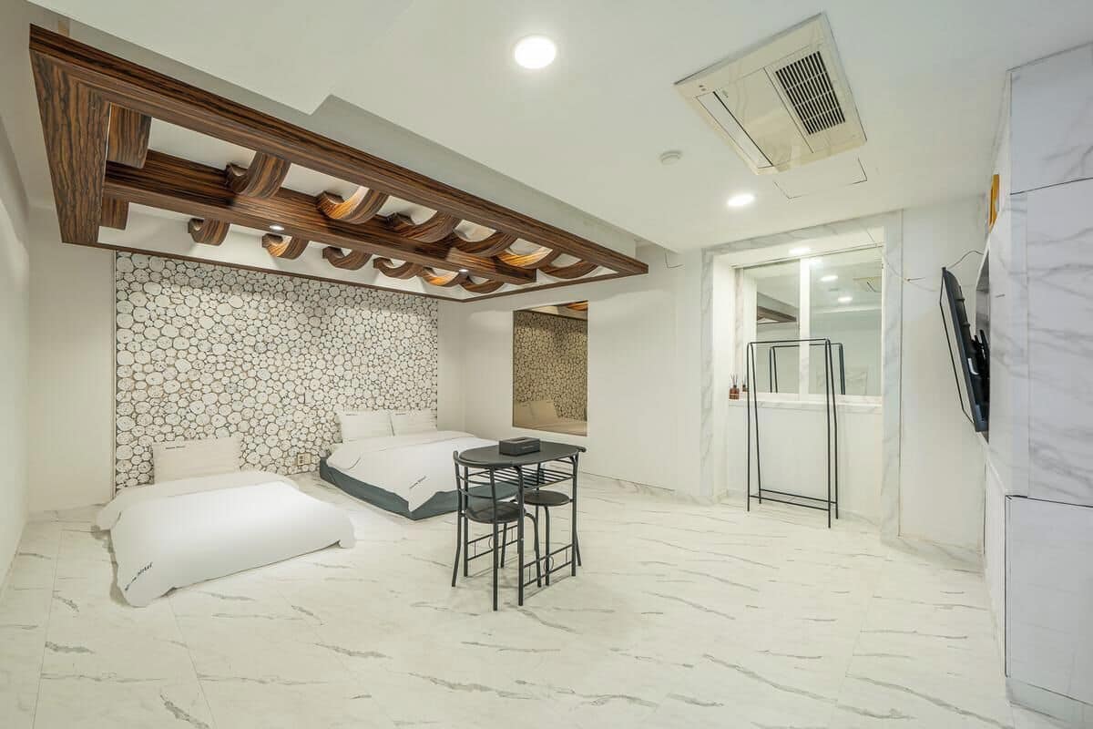 A compact room with a bed, a small table, and a refrigerator.