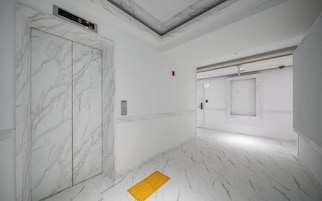 A hallway with marble floors, a door, and a yellow tactile path.