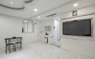 A modern bathroom with a marble floor, a sink, a mirror, and a television mounted on the wall.