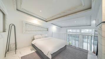 Ein modernes Schlafzimmer mit einem großen Bett, einer Marmorwand und einem Balkon mit Blick auf die Stadt.