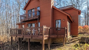 Eine zweistöckige Holzhütte mit Balkon, umgeben von Bäumen.