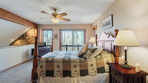 Ein Schlafzimmer mit einem großen Bett, einem Deckenventilator, einer Steinwand, einem Fenster und einer Lampe.