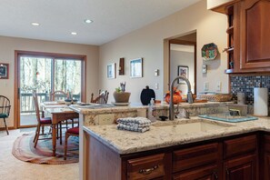 Una cucina con una grande isola, lavello doppio, mobili in legno e un'area pranzo con sedie e tavolo.