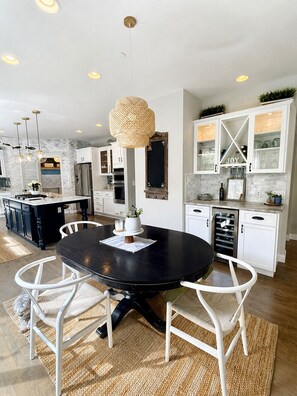 Een moderne keuken met een ronde eettafel, witte stoelen en een centraal keukenblok.
