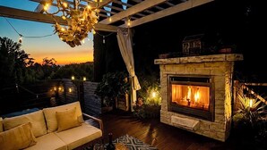 An outdoor patio with a stone fireplace, a wooden sofa, and a patterned rug. - Beautiful Eastside 5 bedroom resort like home with Hot-tub and AC (Newcastle)
