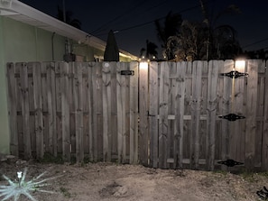 A wooden fence with a gate, a small sign, and a light fixture. - Waterfront Studio w/ Private Entry • Manatees + Dolphins • 1 Mile to Beach (Satellite Beach)
