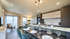A modern kitchen with a dining area, featuring a central island, built-in appliances, and a seating arrangement. - Host Stay Kingfisher Lodge Amotherby (Malton)