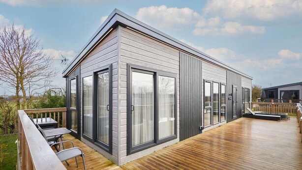 A modern house with a deck, large sliding glass doors, and a wooden exterior. - Host Stay Kingfisher Lodge Amotherby (Malton)