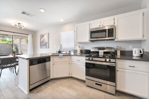 A modern kitchen with stainless steel appliances, white cabinetry, and a dishwasher. - Modern 3BR Home | Pets+7 Min to Airport+Parking (Las Vegas)