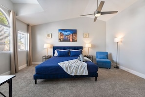 A bedroom with a bed, two bedside tables, a standing lamp, a chair, and a ceiling fan. - Modern 3BR Home | Pets+7 Min to Airport+Parking (Las Vegas)