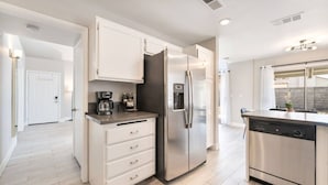 Una cocina moderna con refrigerador, cafetera y lavavajillas.