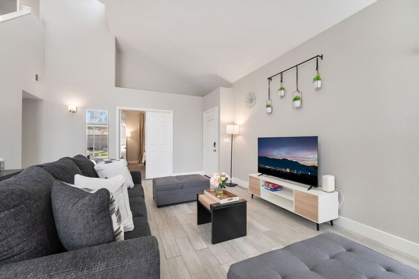 A modern living room with a flat-screen TV, grey sofas, a coffee table, and a TV stand.