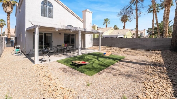 Una casa de dos pisos con un patio, una parrilla y un pequeño jardín.