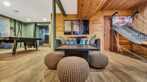 Un interior moderno con una mesa de billar, un sofá con cojines de colores y una hamaca.