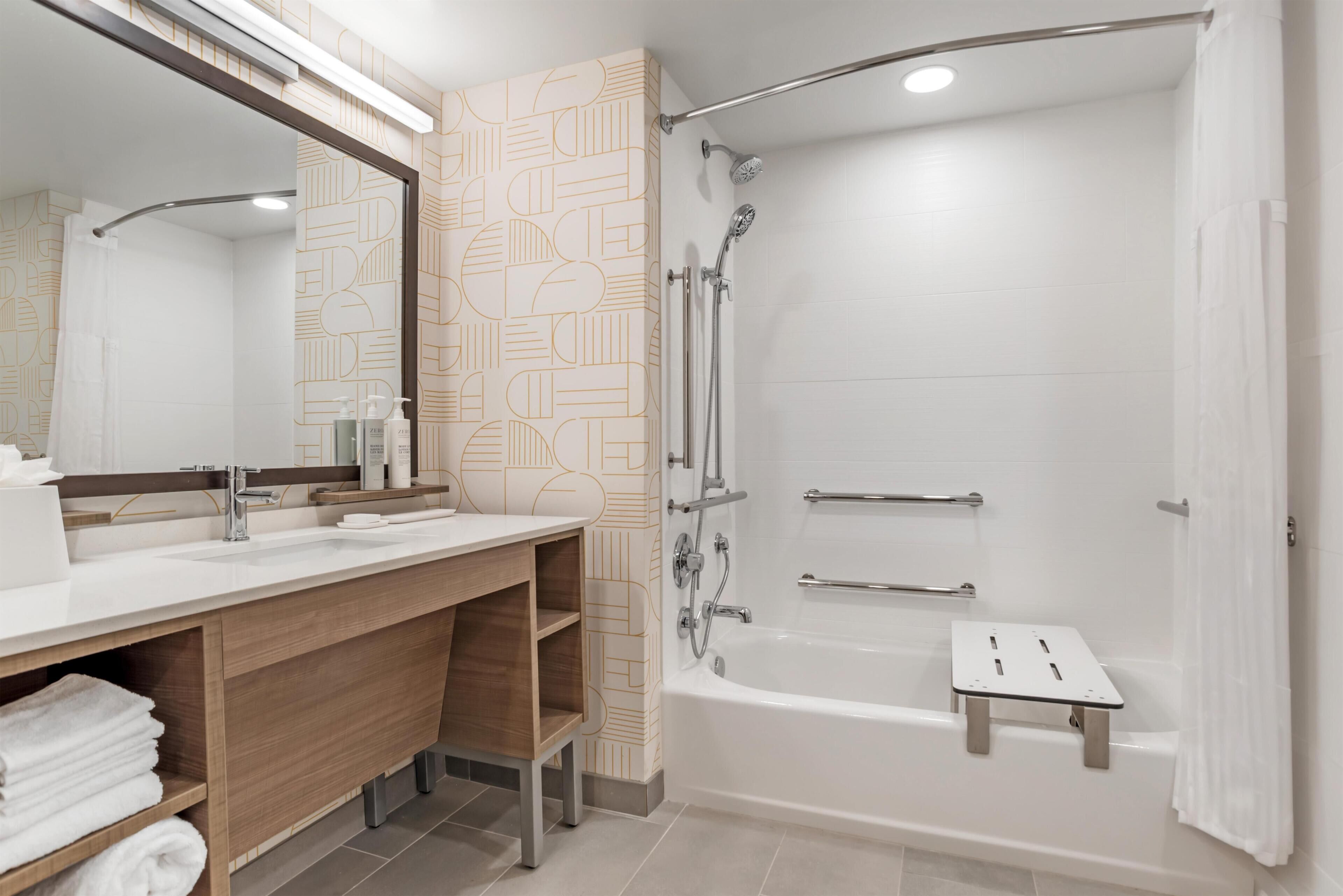 Une salle de bain moderne avec un grand miroir, deux lavabos, une douche et une baignoire.