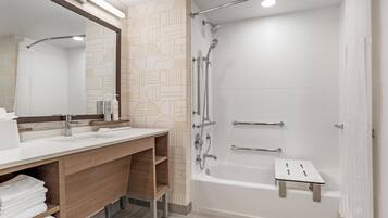 A modern bathroom with a large mirror, two sinks, a shower, and a bathtub.