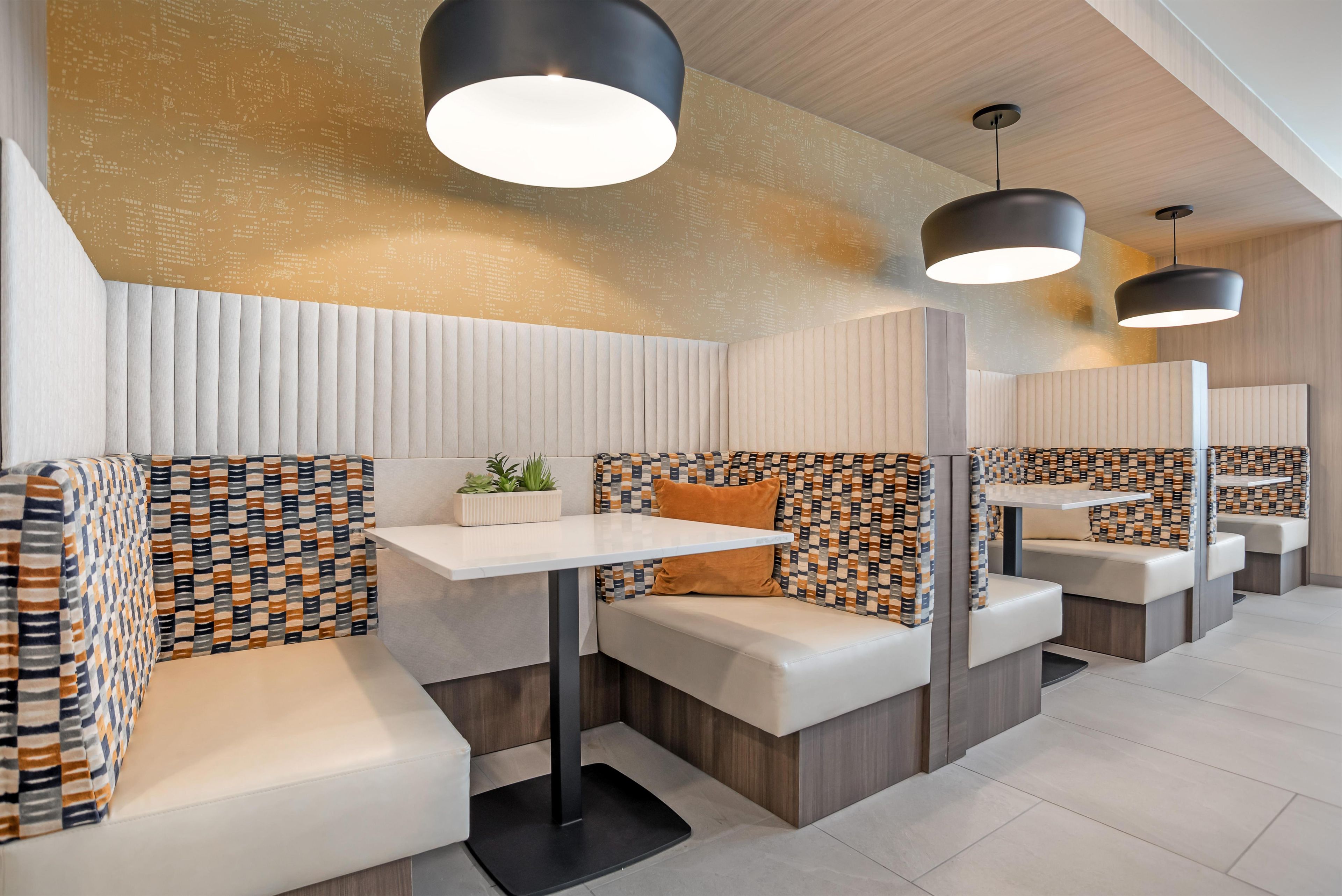 A modern interior with seating areas, pendant lighting, and a patterned wall.