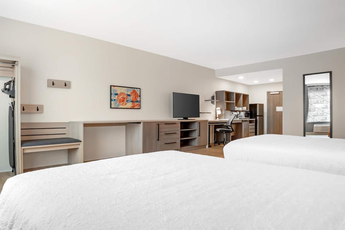 Une chambre d’hôtel avec deux lits, un bureau, une télévision, une armoire et une salle de bain.