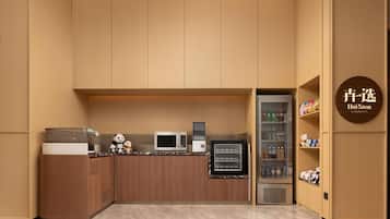 A compact kitchen with wooden cabinets, a microwave, a refrigerator, and a small pantry area.