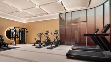 Academia moderna com equipamentos de cardio, máquinas de peso e um espelho grande.