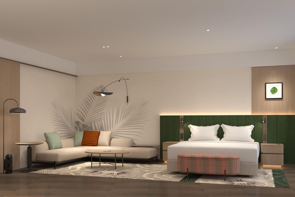 Ein modernes Schlafzimmer mit Bett, einer Couch, einem kleinen Tisch und einer Lampe.