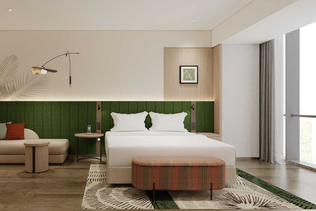 Ein modernes Hotelzimmer mit einem großen Bett, einer Sitzecke, einem kleinen runden Tisch und einer Wanddekoration.