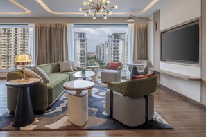 A modern living room with a sofa, armchairs, a coffee table, and a TV. - Hilton Lucknow Gomti Nagar (Lucknow)