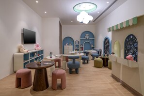 A children's play area with round tables, colorful stools, and shelves with toys.