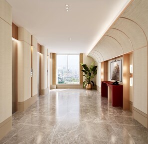 A modern hotel lobby with a marble floor, a reception desk, a large potted plant, and a city view through the glass doors.