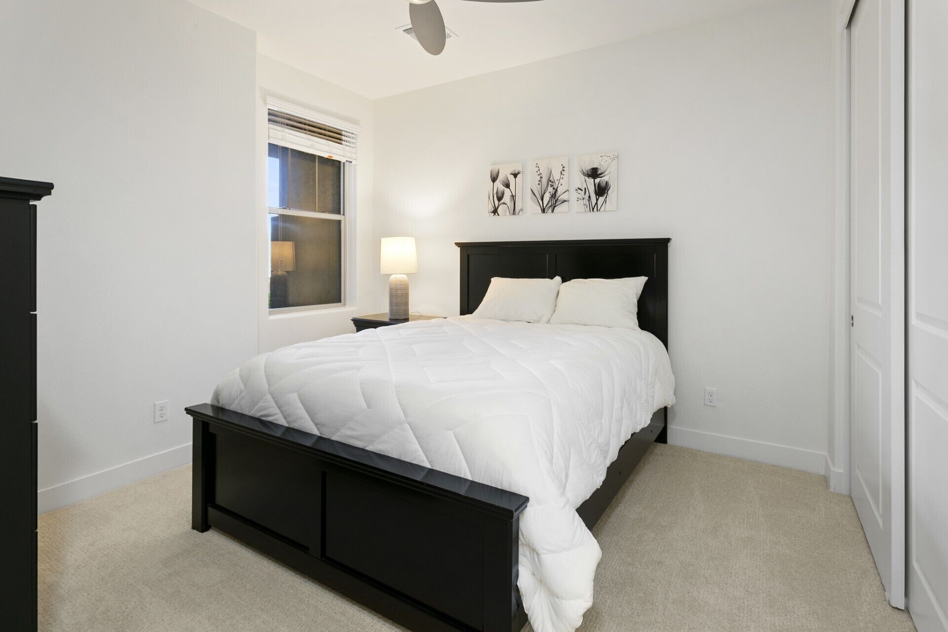 A bedroom with a bed, a nightstand, a lamp, and wall art.