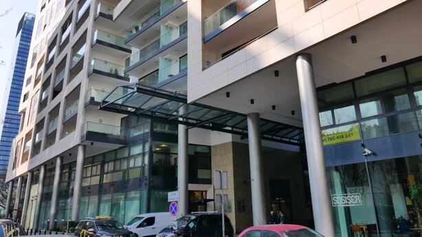 A multi-story building with a glass facade, a covered entrance, and a visible restaurant sign. - Serene 1-bedroom apartment in the heart of Warszawa (Warszawa)