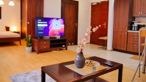 A modern living room with a flat-screen TV, wooden furniture, a vase with flowers, and a dining area. - Serene 1-bedroom apartment in the heart of Warszawa (Warszawa)