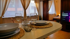 A dining area with a table set for four, including plates, glasses, and a teapot. - Serene 1-bedroom apartment in the heart of Warszawa (Warszawa)