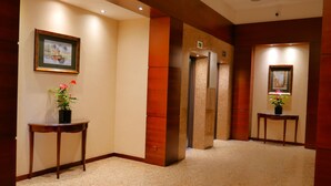 A hallway with a carpeted floor, wooden walls, and two small tables with potted plants. - Serene 1-bedroom apartment in the heart of Warszawa (Warszawa)