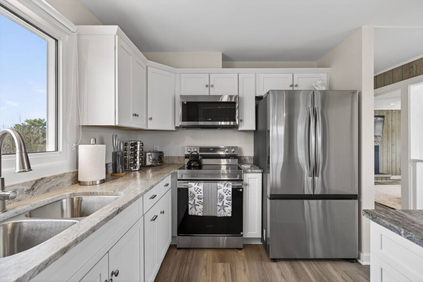 A modern kitchen with white cabinets, stainless steel appliances, a microwave, oven, and refrigerator.