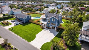 A residential area with houses, a swimming pool, and a well-maintained lawn. - New! Luxe Sandbridge Beach, Pool, Hot Tub (Virginia Beach)