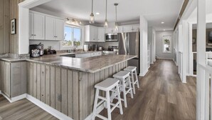 A modern kitchen with a large island, white cabinetry, and pendant lighting. - New! Luxe Sandbridge Beach, Pool, Hot Tub (Virginia Beach)