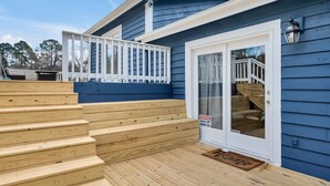 A wooden deck with a 'Welcome Home' mat, a white door with a security warning sign, and a blue exterior wall. - Unique Durham Cabin with Hot tub and close to Duke (Durham)